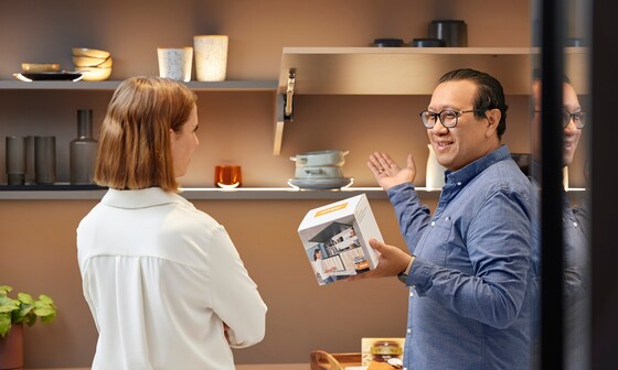 A Blum expert shows a woman in the showroom the advantages of using displays to promote Blum products.